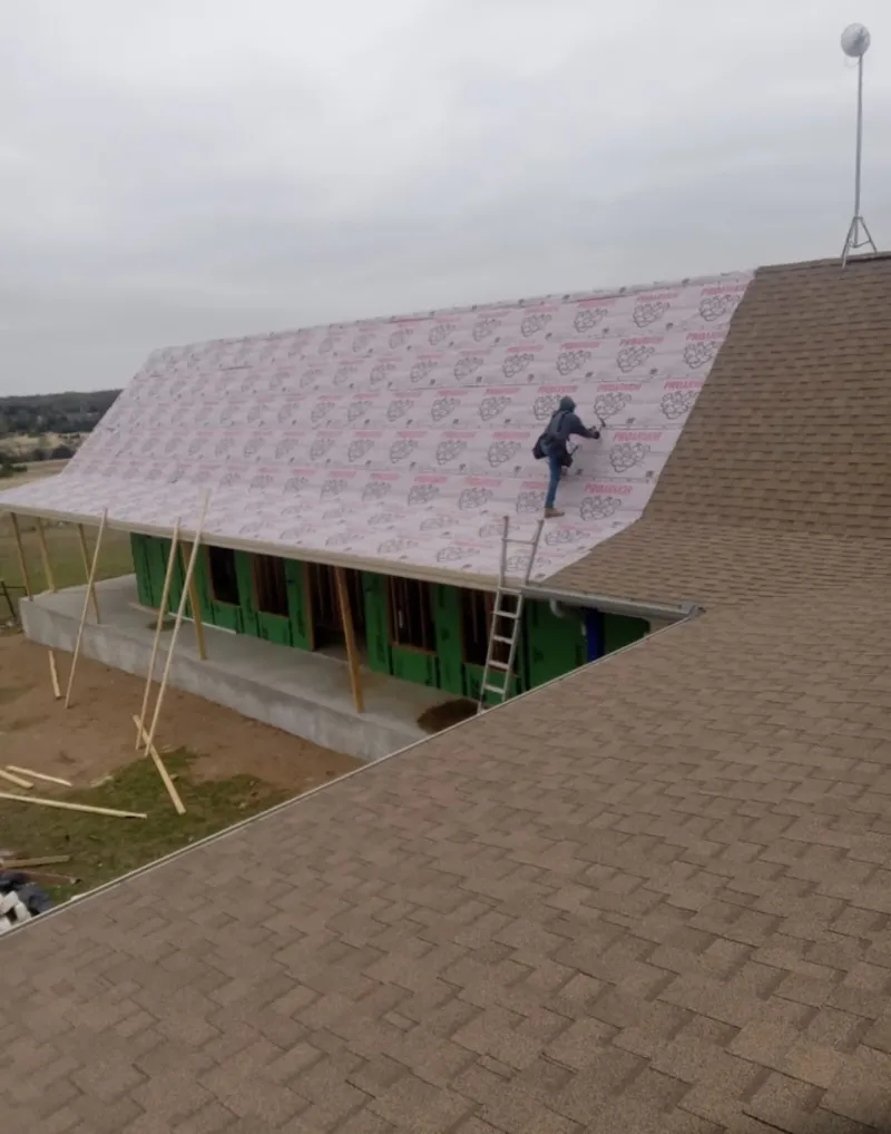 Worker preparing underlayment for a metal roof installation in Manlius